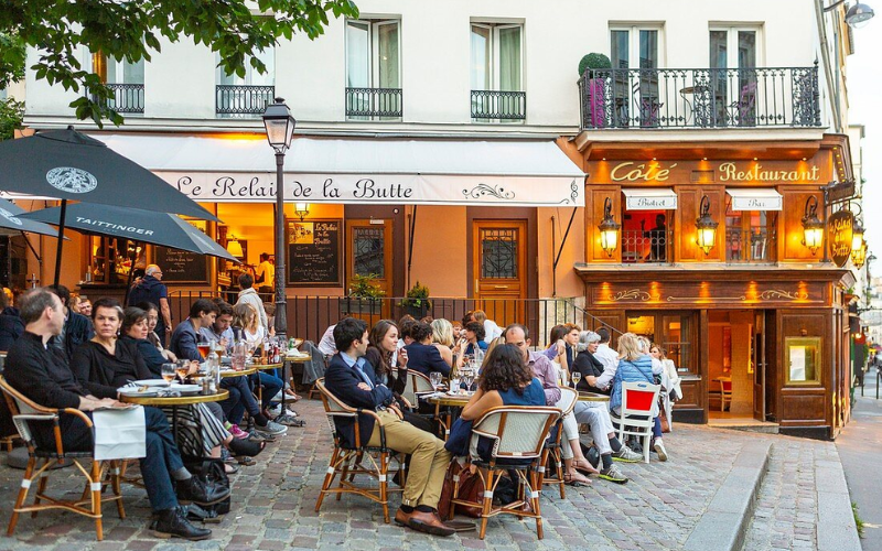 Enjoying Drinks And Lively Conversations At A Charming Café In Montmartre, Paris